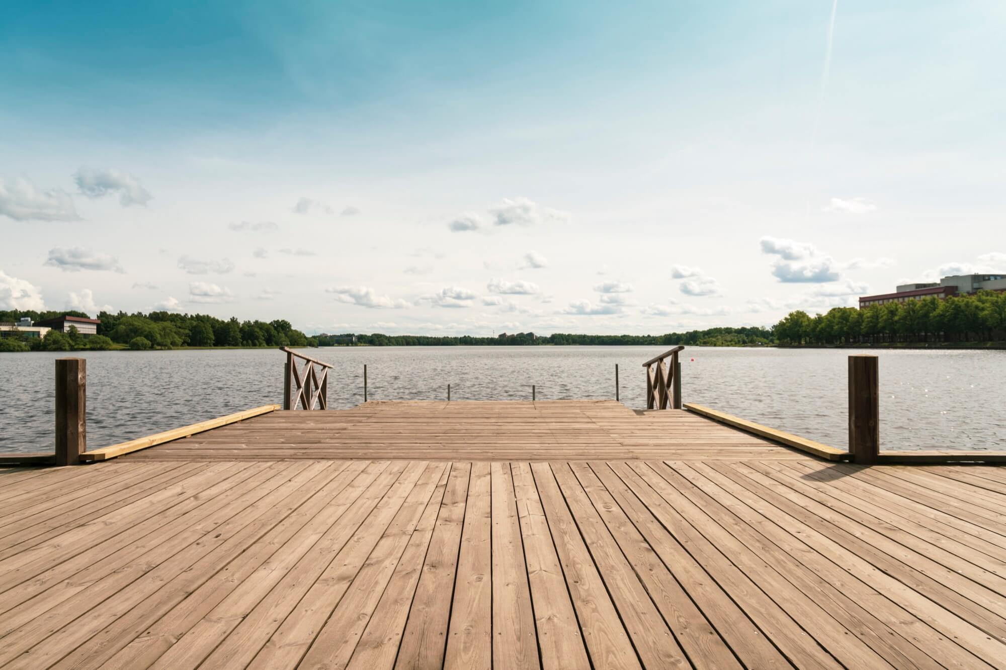 Laiturimainen terassi järven rannalla, jossa on kaiteet ja rauhallinen vesi.
