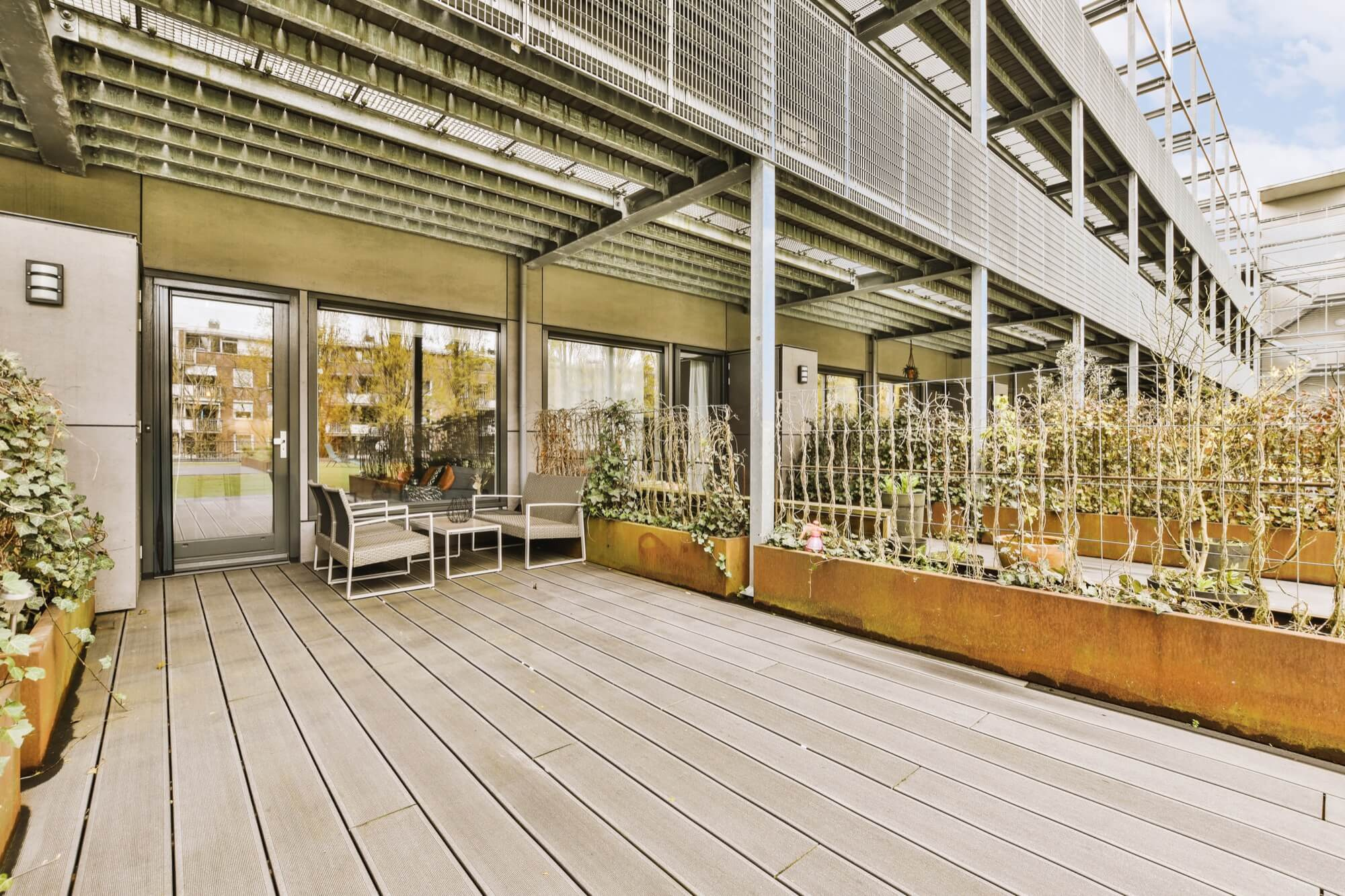 Tilava terassi asuinalueella, jossa on komposiittiterassi, ulkokalusteet ja istutukset.